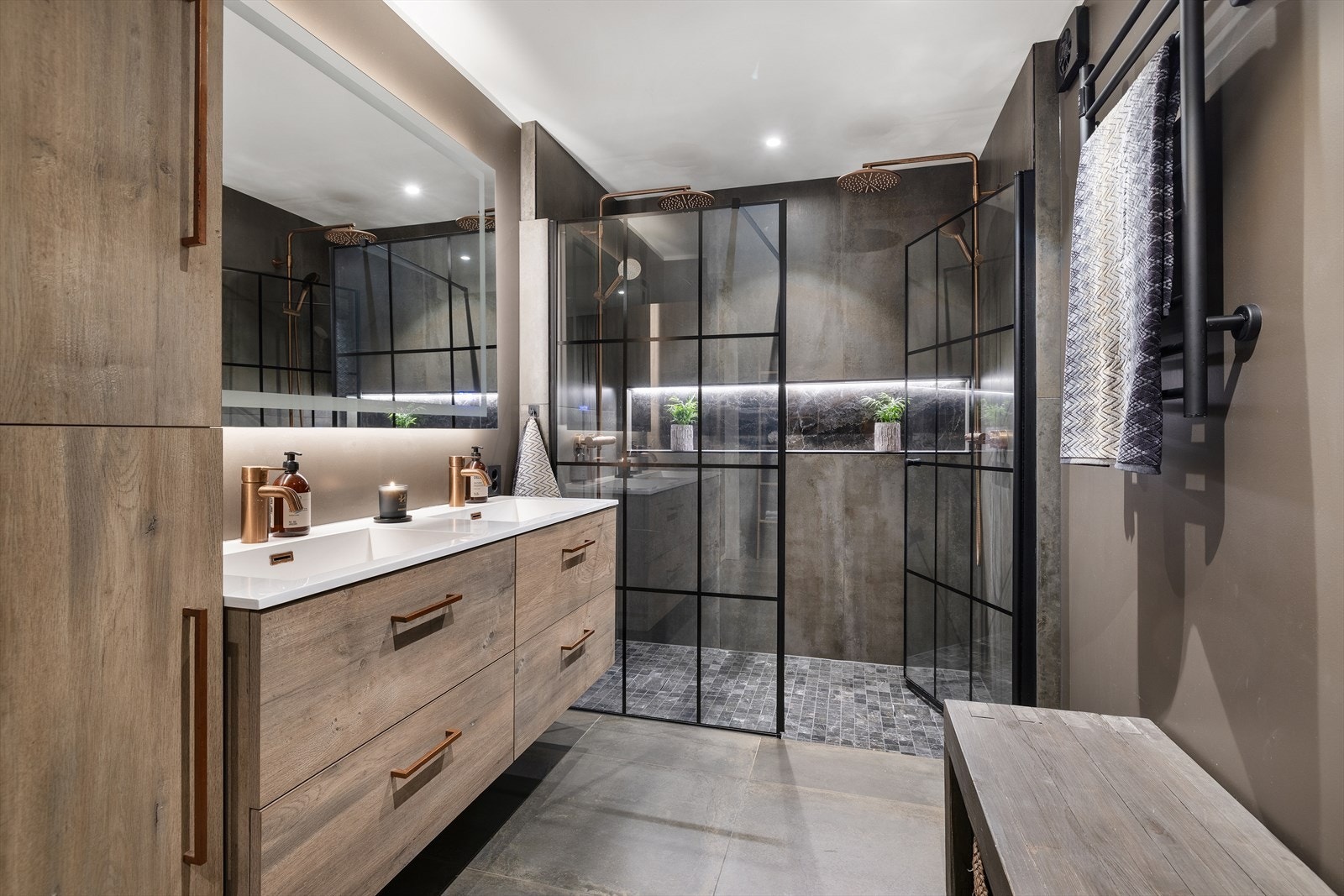 Badet har et moderne dusjhjørne med glassdører, vegghengt toalett og dobbel servant. Galleribilde