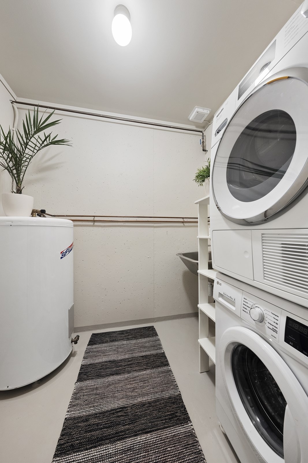 Praktisk vaskerom med opplegg til vaskemaskin og tørketrommel, utslagskum og varmtvannstank Galleribilde