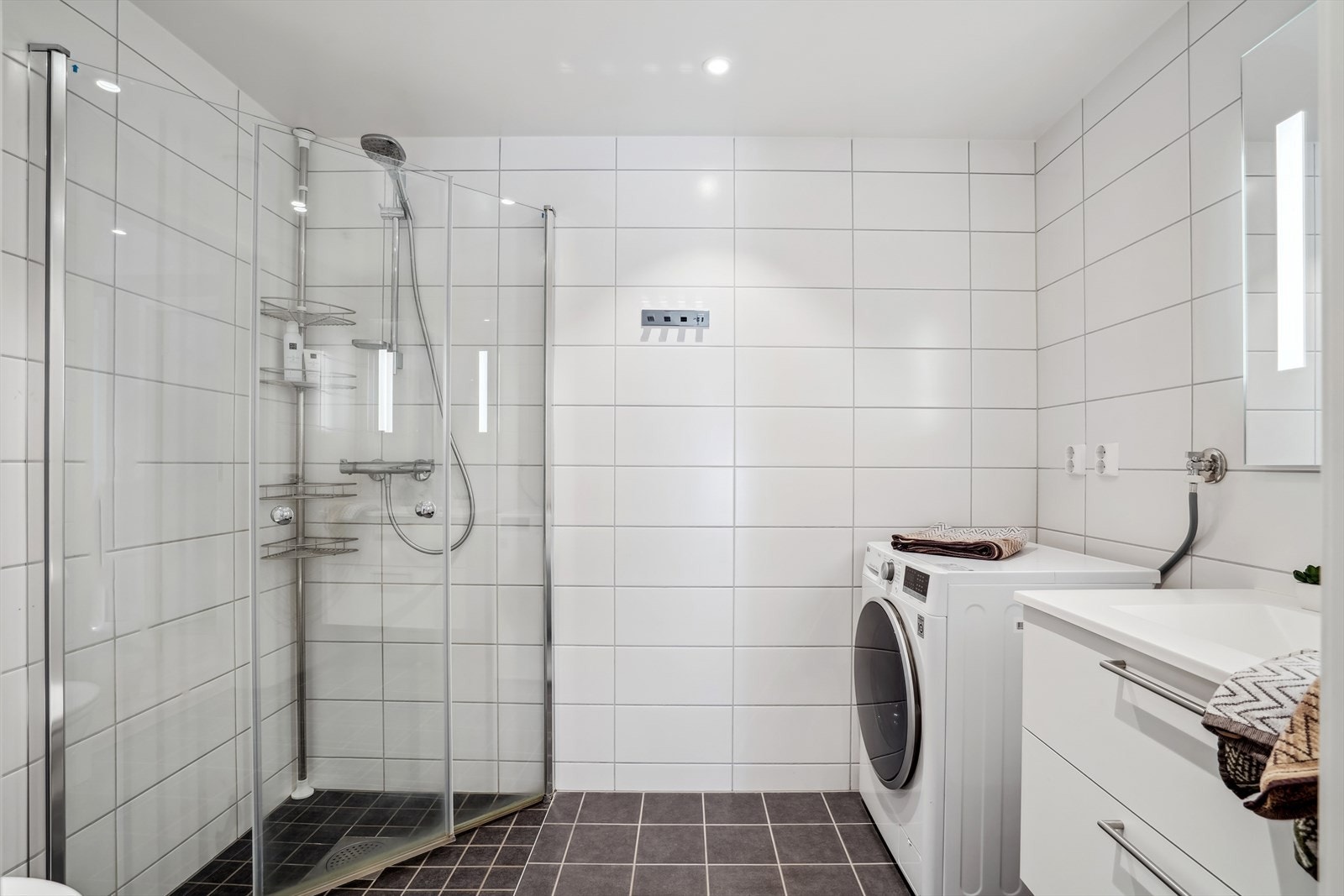 Badet er helfliset og av god størrelse. Det inneholder vegghengt toalett, dusj med vendbare dører, og ellers vask med skapinnredning og speil Galleribilde