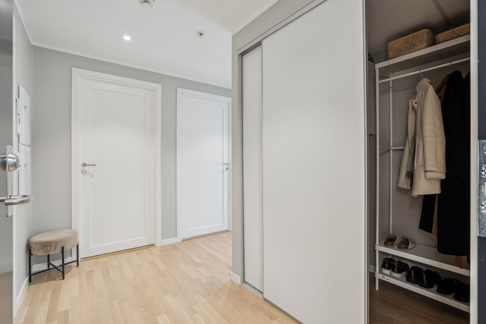 Entréen gir et ryddig og praktisk førsteinntrykk med plass til oppbevaring av yttertøy og sko i stor skyvedørsgarderobe Galleribilde