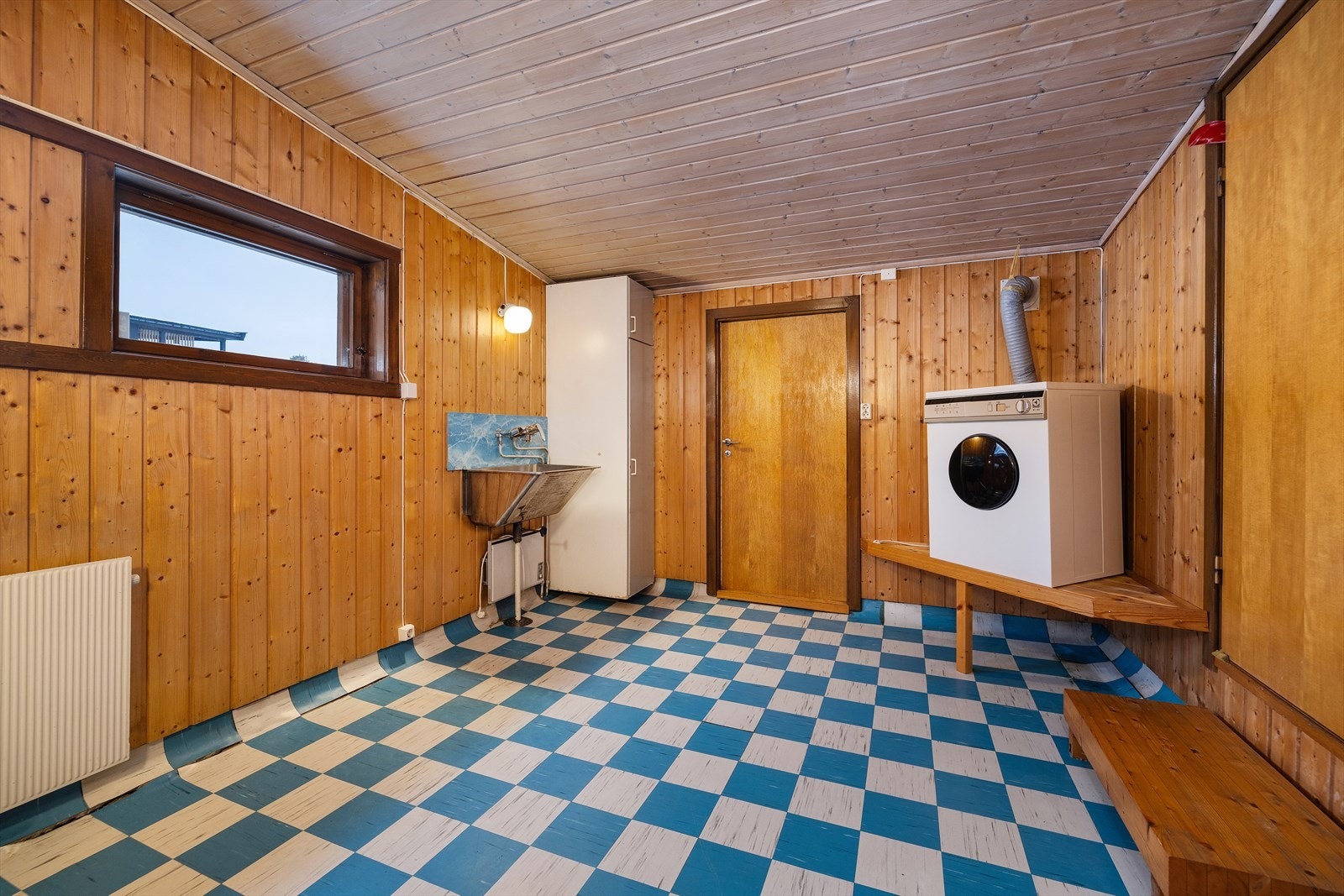 Et stort vaskerom med egen utgang, opplegg for vaskemaskin og utslagsvask. Galleribilde