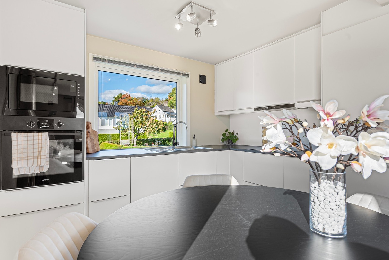 Innredningen har hvite, glatte fronter med diskré håndtak, takhøye overskap og grå laminatbenkeplater. Galleribilde