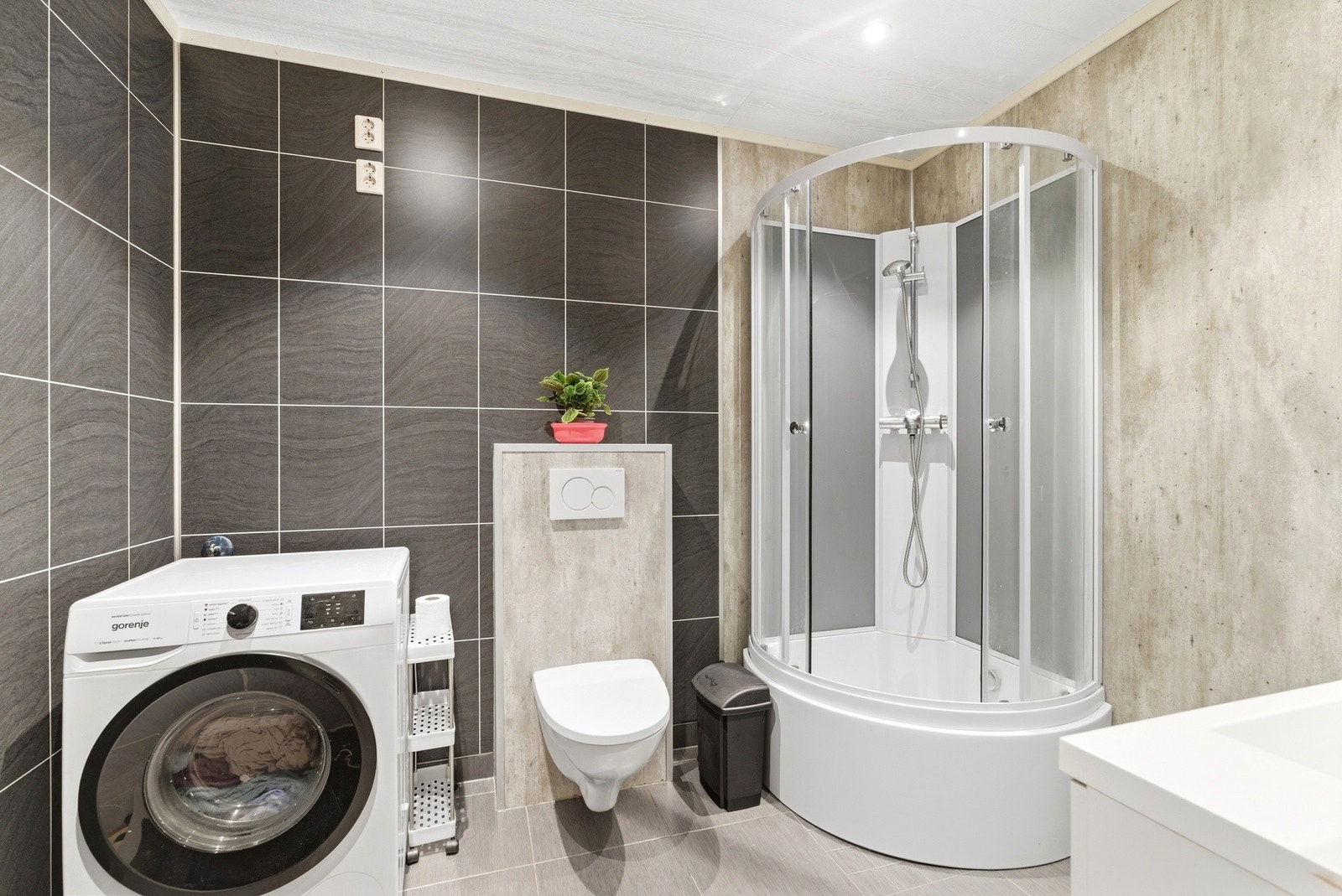 Badet har en moderne stil og er utstyrt med dusj, toalett og opplegg for vaskemaskin Galleribilde