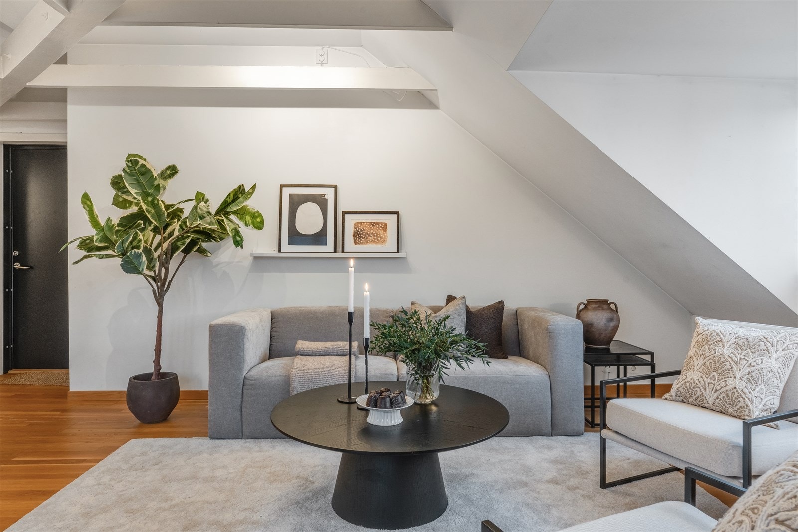 Lys og lekker stue med skråtak som gir leiligheten en særegen atmosfære Galleribilde