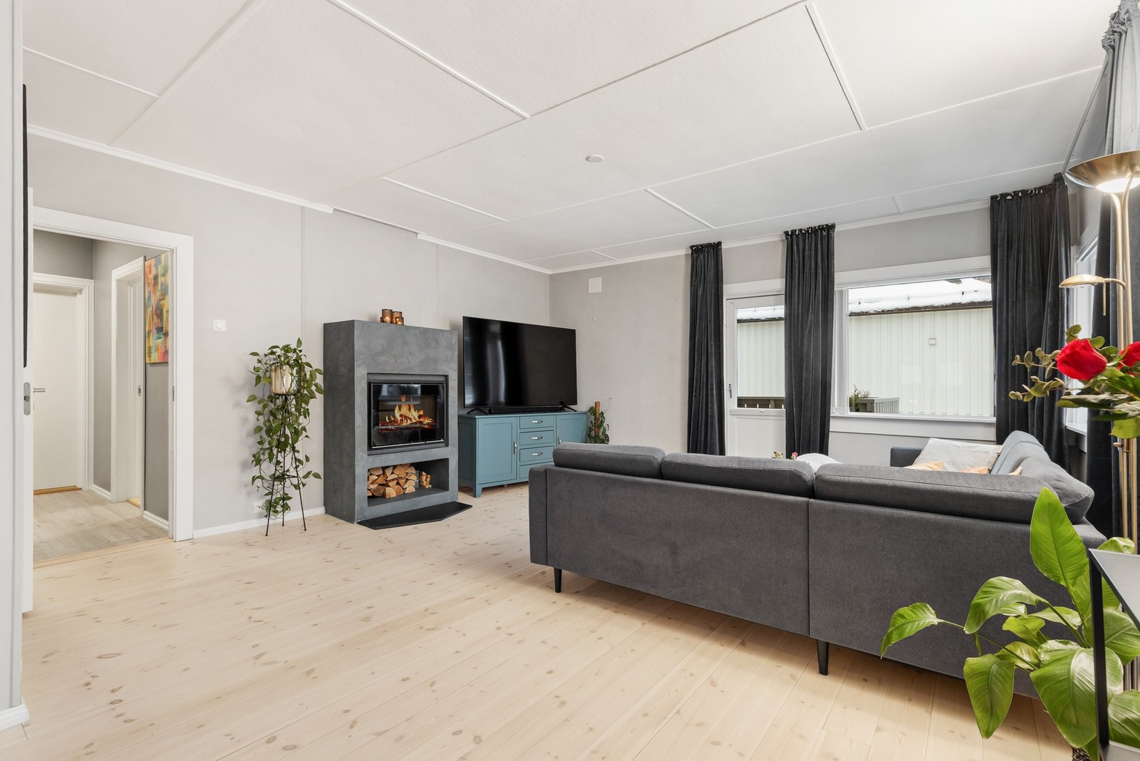 Lys og innbydende stue med furugulv, malte flater på vegger og takplater i himling Galleribilde