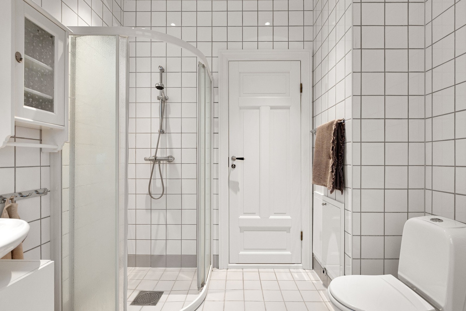 Baderommet er utstyrt med dusjkabinett, servantskap med glatte fronter og speil med lysarmatur over Galleribilde