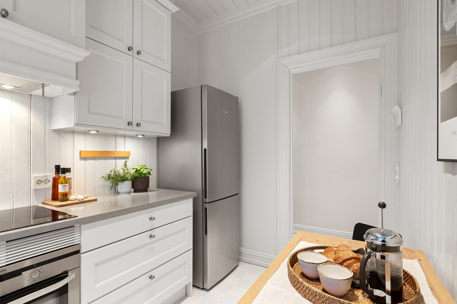 Kjøkkenet har lys under overskap, integrerte hvitevarer som induksjonsplatetopp, stekeovn og oppvaskmaskin, samt plass til kjøle-/fryseskap Galleribilde