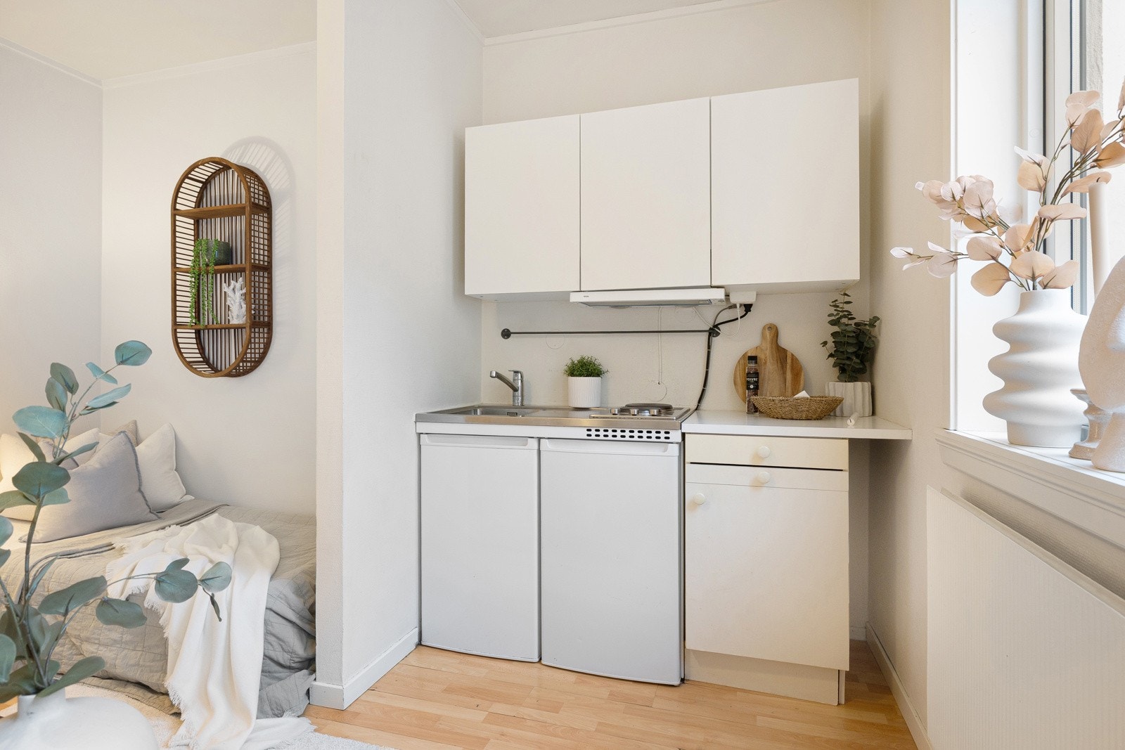 T-kjøkken fra 2023 og eldre kjøkkeninnredning med hvite glatte fronter, laminatbenkeplate og benkeplate i rustfritt stål med innfelt vaskekum og ettgreps krummet armatur og 2 platetopper Galleribilde