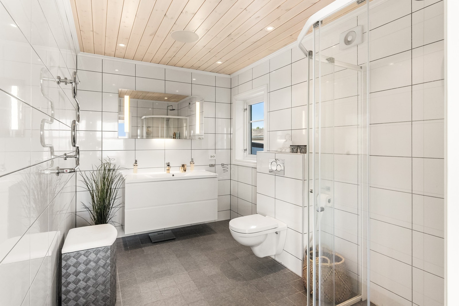 Badet til hovedsoverommet er lekkert innredet med dusjhjørne, vegghengt toalett, servant i innredning og håndkletørker Galleribilde