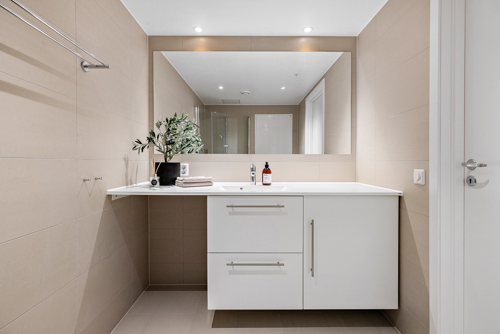 Lyst og delikat flislagt bad med opplegg til vaskemaskin. Galleribilde