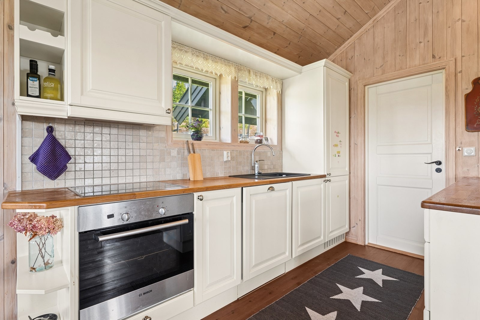 Kjøkkeninnredningen er pent utført med hvite, profilerte fronter og heltre benkeplate i eik med nedfelt kjøkkenkum. Galleribilde