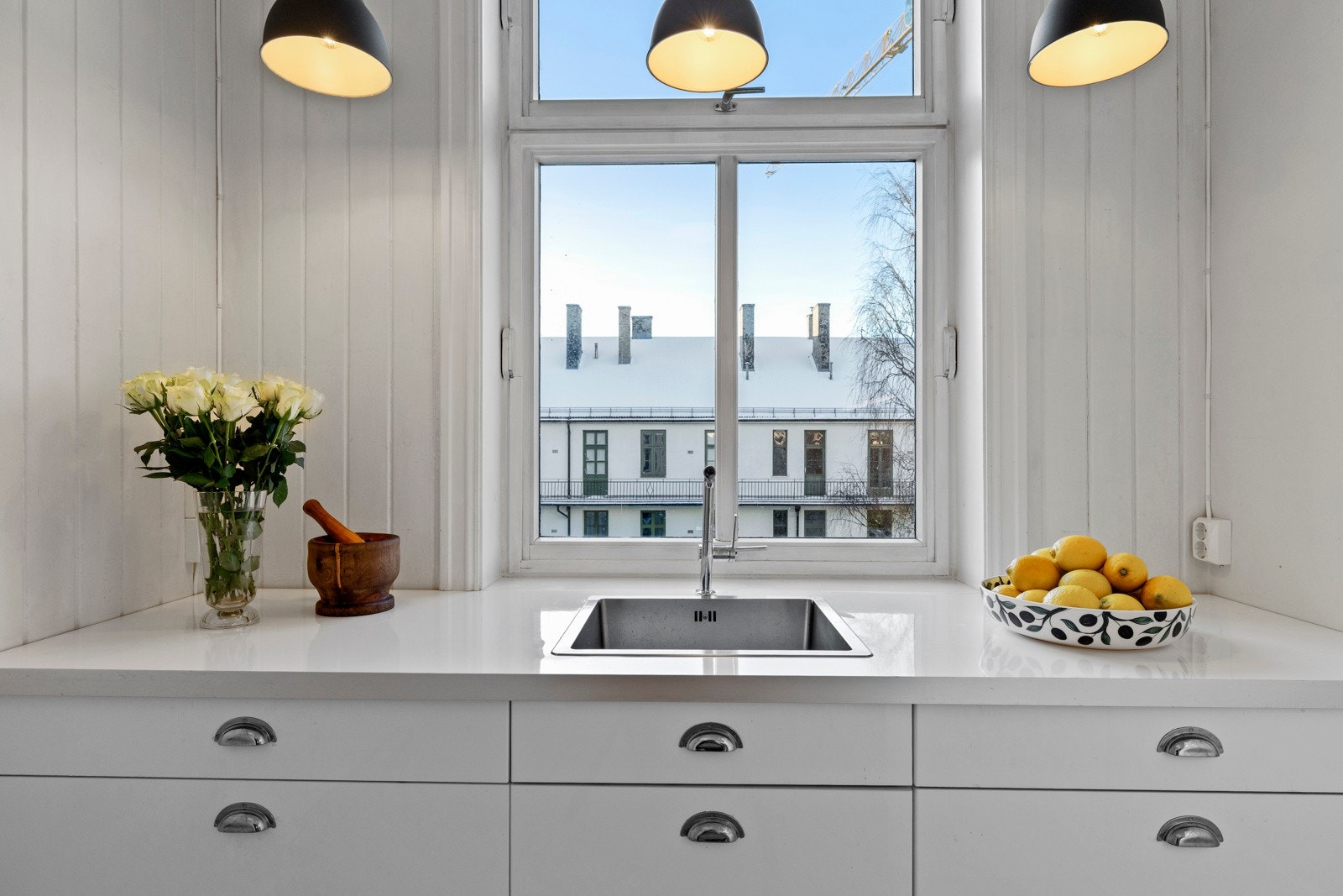 Det er laminat benkeplate med nedfelt oppvaskkum, samt delvis backsplash med flis og panel. Galleribilde