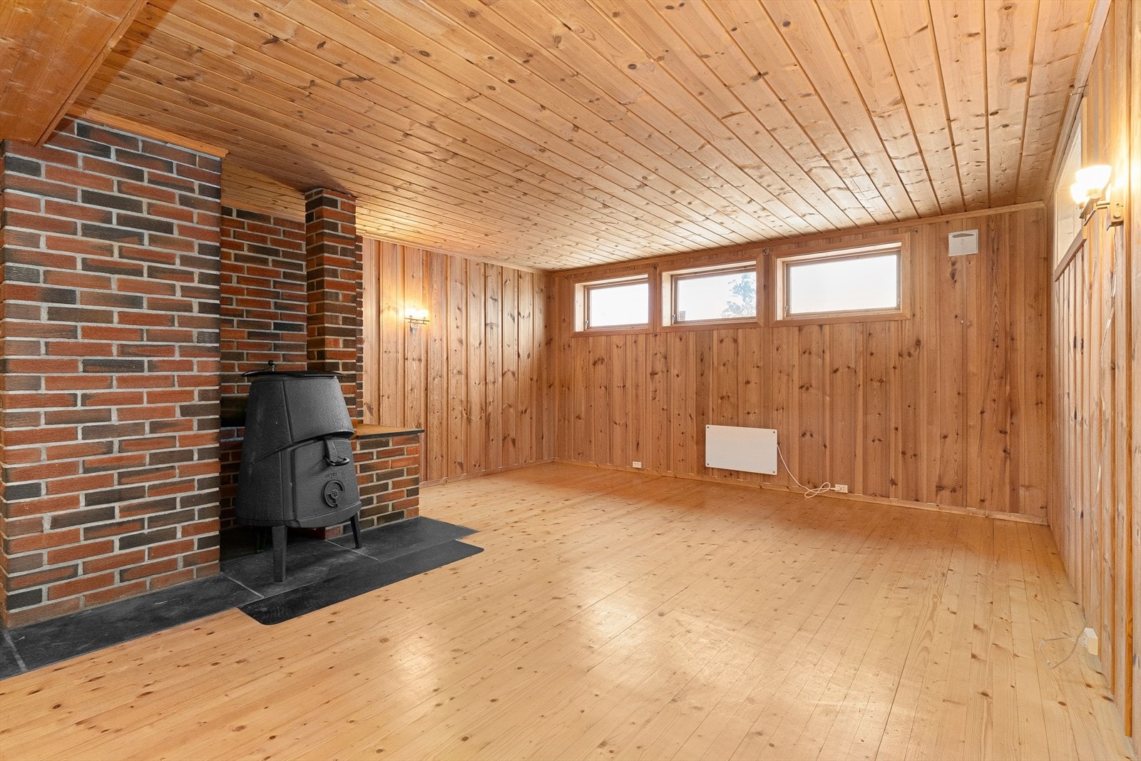 Innredet rom i kjeller med vedovn. Galleribilde