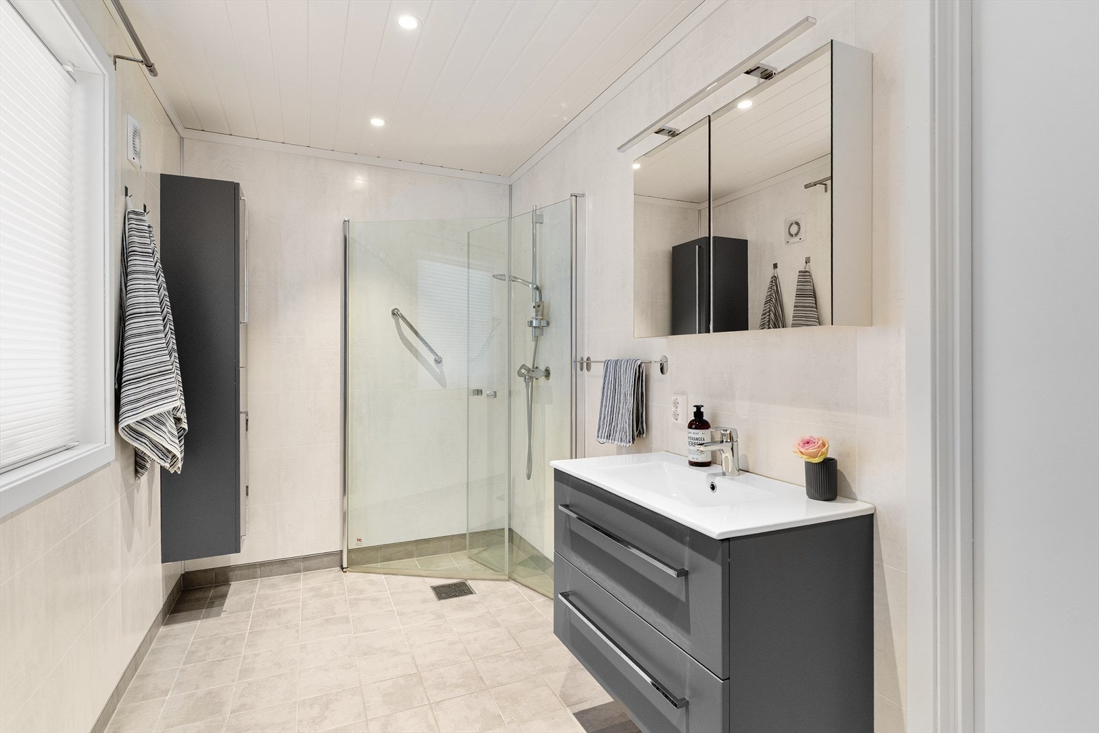 Rommet har innredning med nedfelt servant i baderomsinnredning, speilskap, veggmontert toalett og dusjvegger/hjørne. Galleribilde