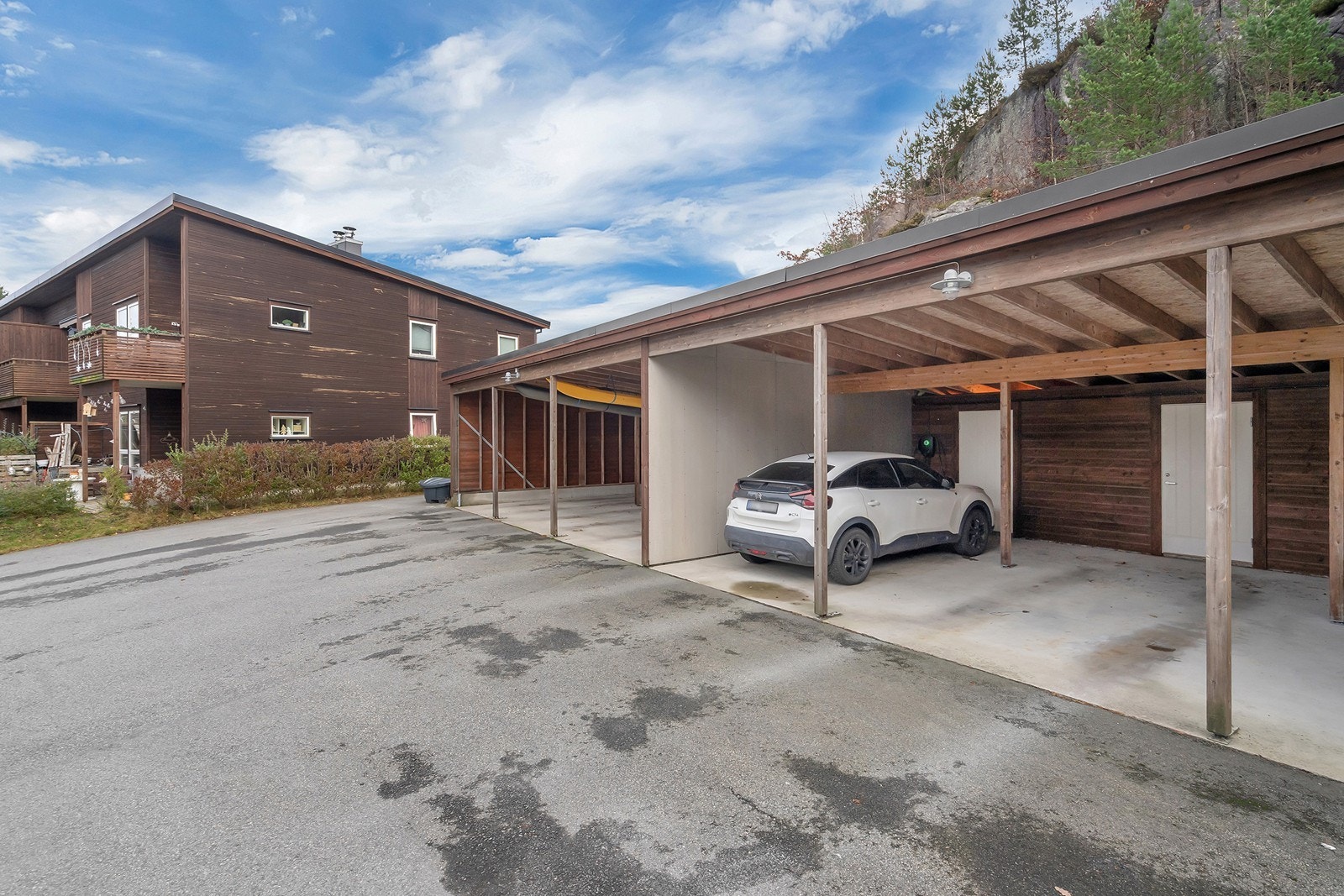 Parkering i carport med tilhørende sportsbod og elbil-lader Galleribilde