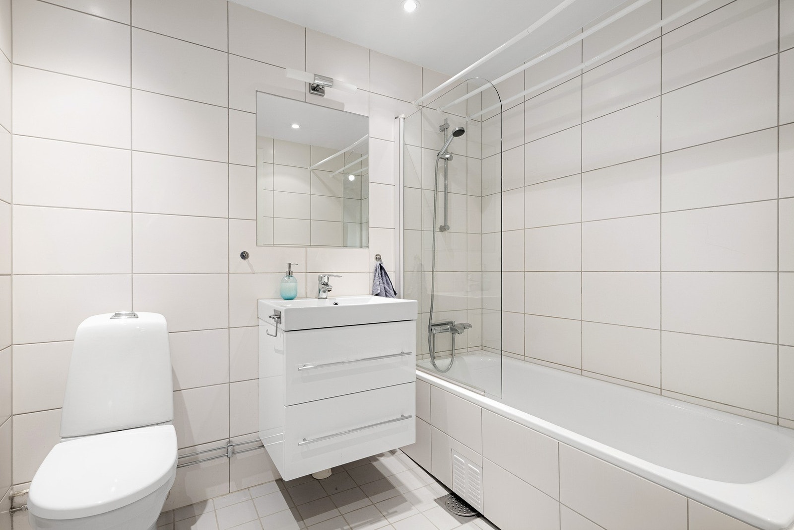 Badet er innredet med innebygget og flislagt badekar, servant, gulvstående klosett og opplegg for vaskemaskin. Galleribilde