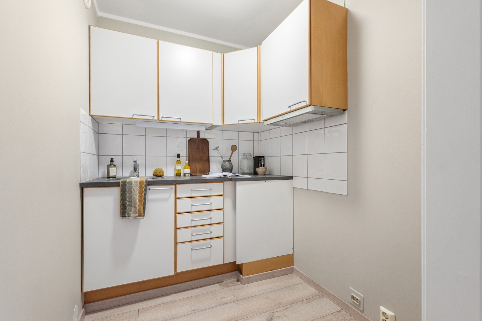 Eldre kjøkken med glatte fronter og laminert benkeplate med oppvaskkum i rustfritt stål med svingbart blandebatteri. Galleribilde