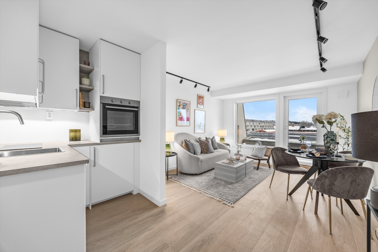 Den åpne løsningen mellom stue og kjøkken gir et sosialt preg, samtidig som kjøkkenets funksjonelle utforming gjør rommet praktisk i bruk. Galleribilde