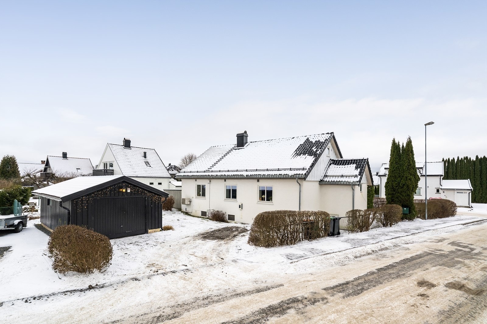 Romslig, gruset gårdsplass med frittstående garasje og mulighet for lading av elbil. Det ble lagt opp ny kurs ved montering av elbillader i 2020. Galleribilde