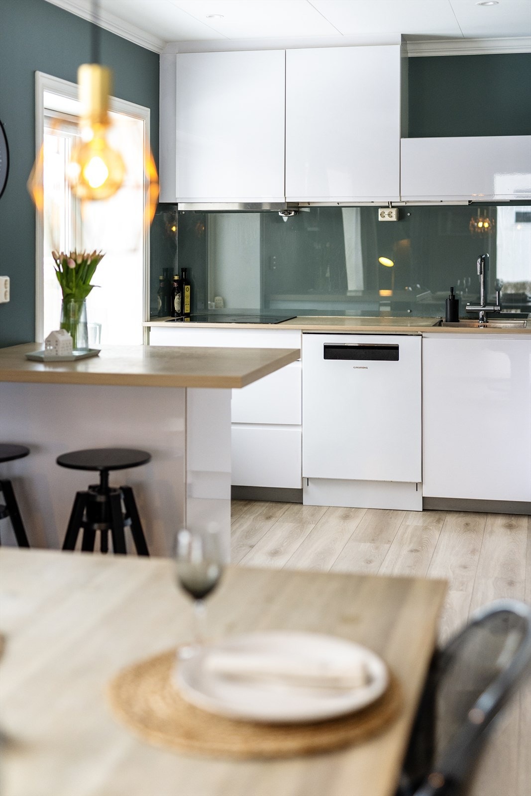 Pent kjøkken i åpen løsning, med lys og takhøy kjøkkeninnredning type Kvik fra 2017. Innredningen har glatte, stilrene fronter i høyglans. Galleribilde