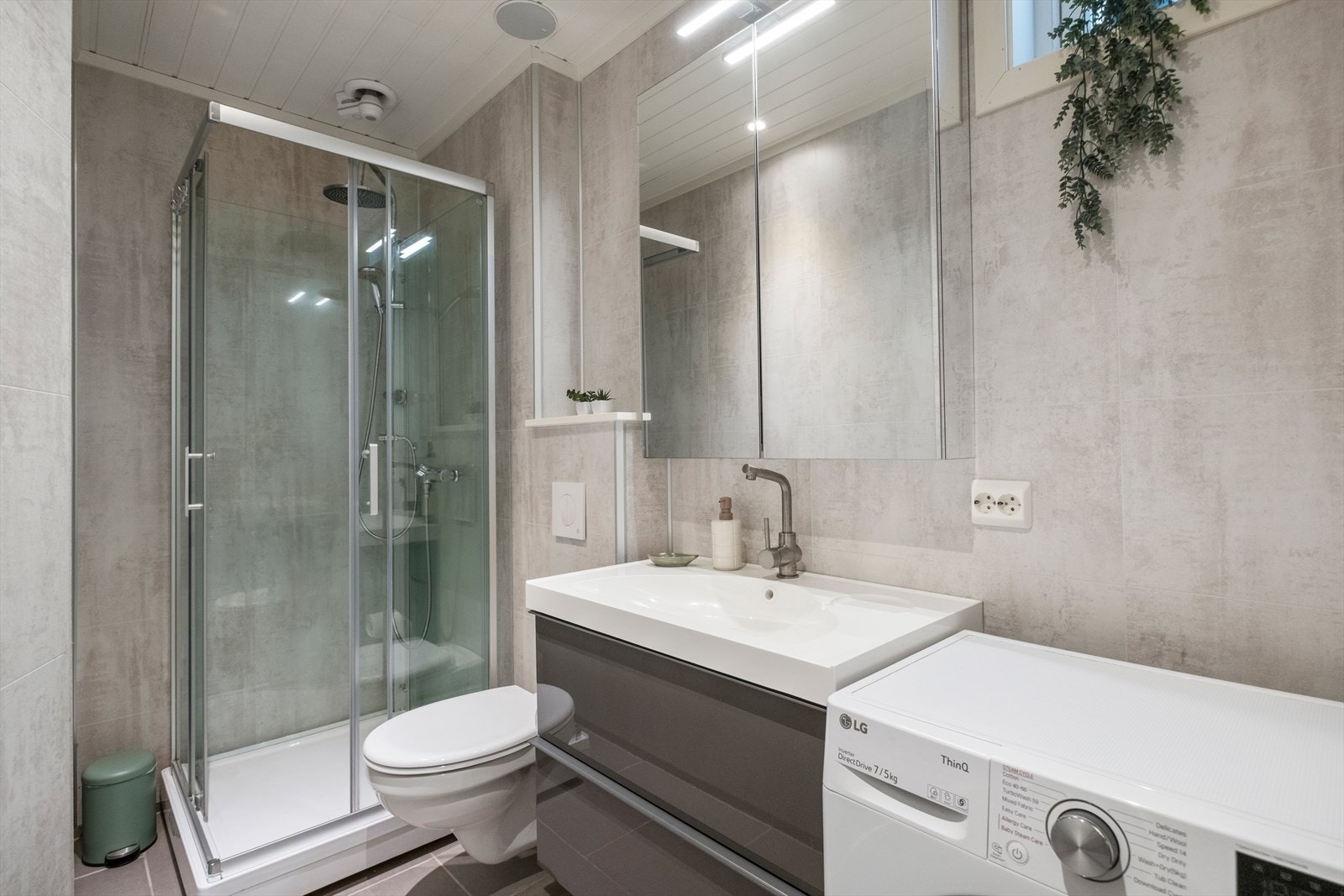 Pent og moderne bad med dusjkabinett, vegghengt toalett og plass til vaskemaskin. Galleribilde