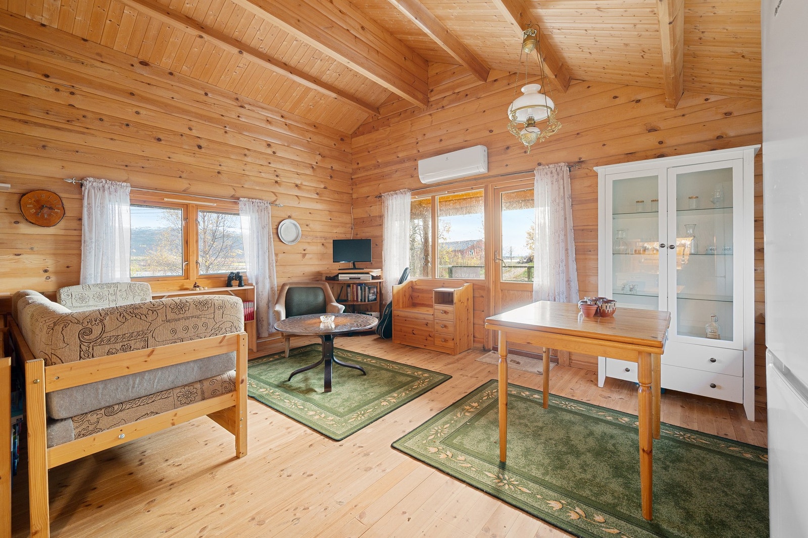 God takhøyde og godt lysinnslipp fra flere stuevinduer gir en romslig og luftig stue Galleribilde