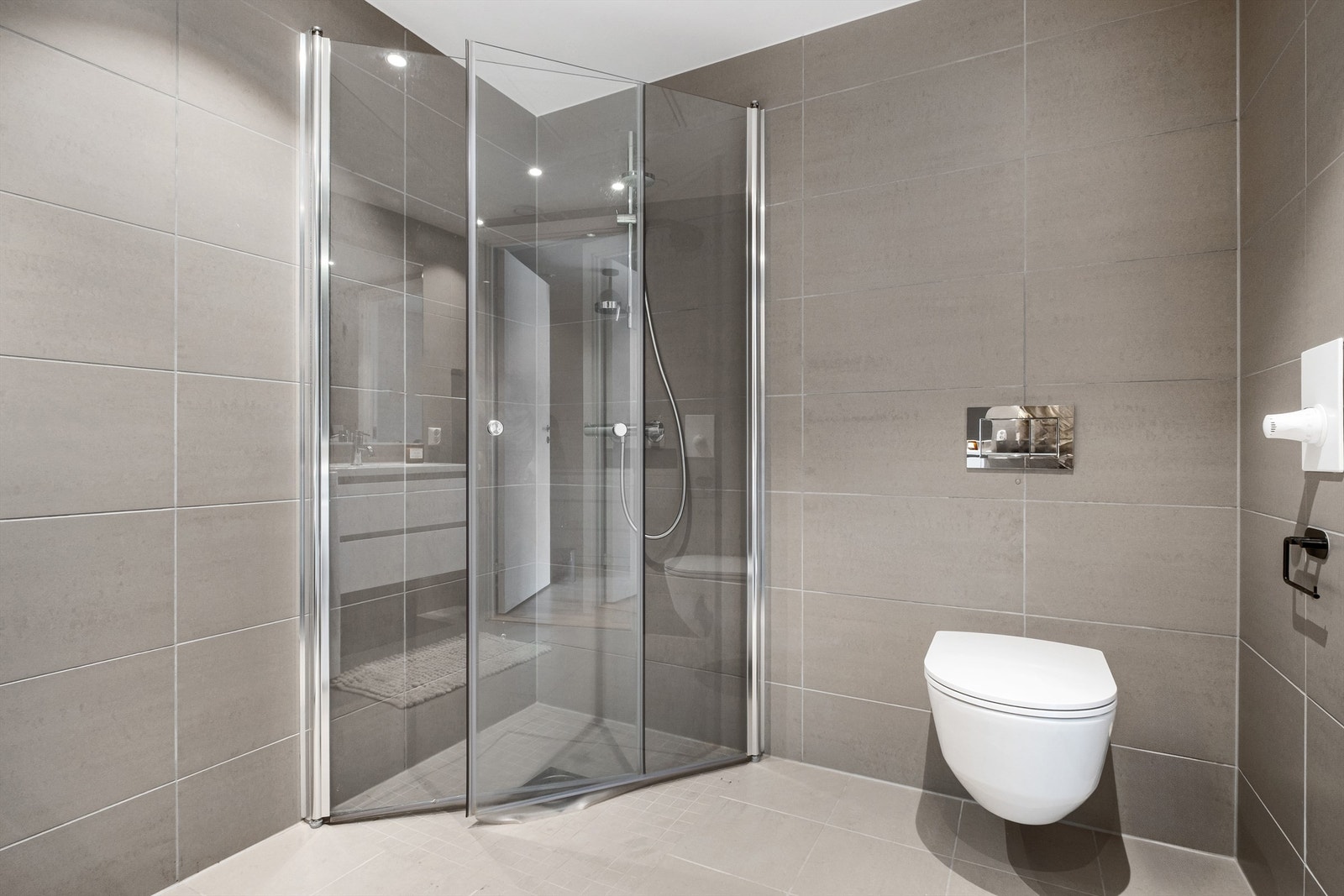 Dusj med innfellbare glassdører og vegghengt toalett. Galleribilde