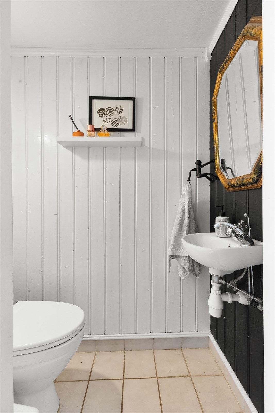 Separat toalettrom med malt panel på vegger, malt slett tak og flislagt gulv, innredet med gulvstående toalett og håndvask. Galleribilde