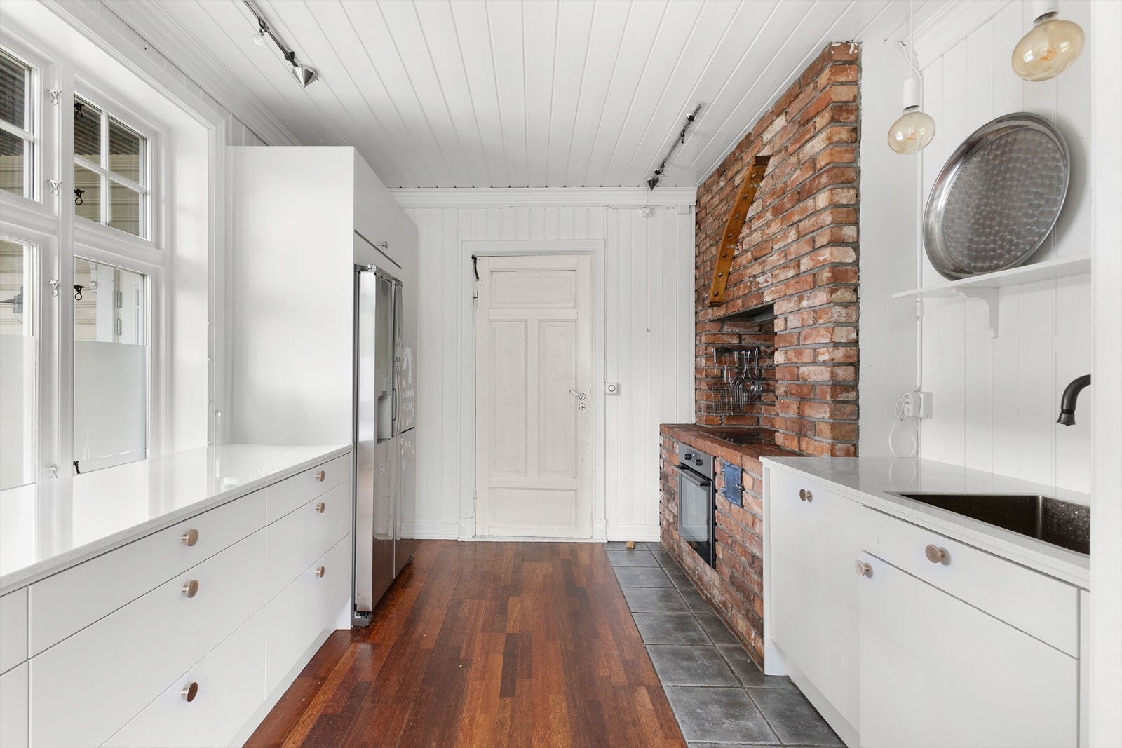 Avdeling med teglstein for innbygd stekeovn og ventilator. Side bye side kjøl/fryseskap i børstet stål m/vann- og isbit-dispenser. Integrerte hvitevarer som oppvaskmaskin, stekeovn, keramisk koketopp. Galleribilde