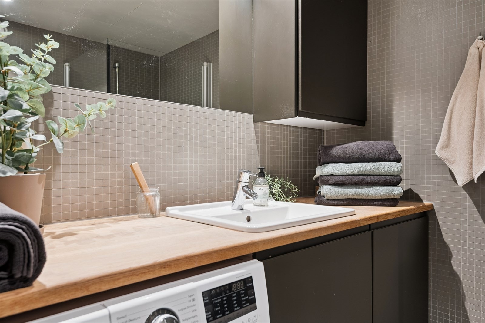 Badet har fliser på gulv og vegger, samt opplegg for vaskemaskin. Galleribilde