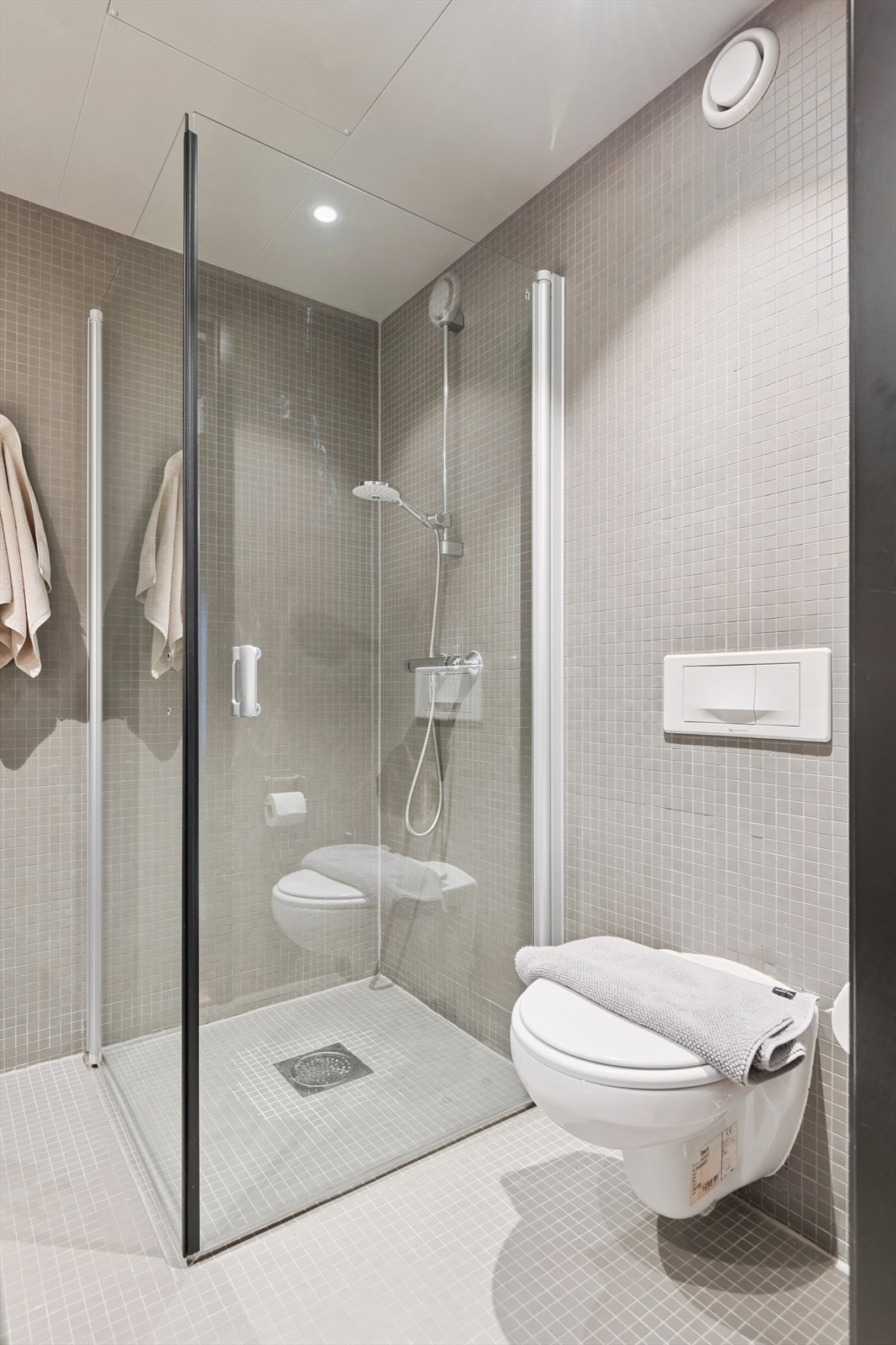 Dusjhjørnet er avskjermet med glassvegger, og toalettet er vegghengt for enkelt renhold. Galleribilde