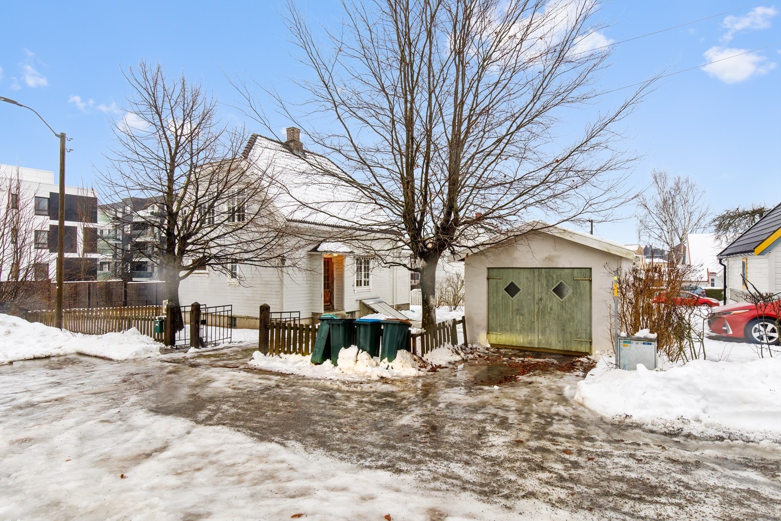 Familiens kjøretøy kan plasseres i frittstående garasje og på eiendommens gårdsplass. Hagen har gressplen i alle retninger og inngangspartiet til eiendommen har både smijernsport og smijernsportal, klassisk montert i tidstypiske søyler av stein. Galleribilde