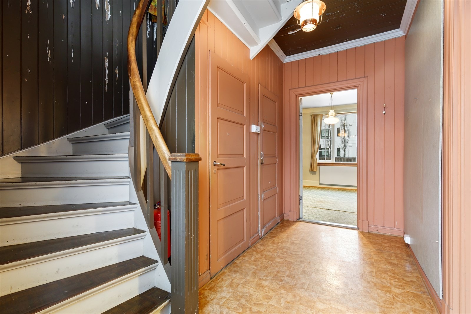 Den orginale, malte tretrappen med tette trinn leder opp til 2. etasje. Innerst i rommet er det lukket trappegang til underetasjen. Det er noe plass til å etablere garderobeløsning for ytterklær og skotøy hvis ønskelig. Galleribilde