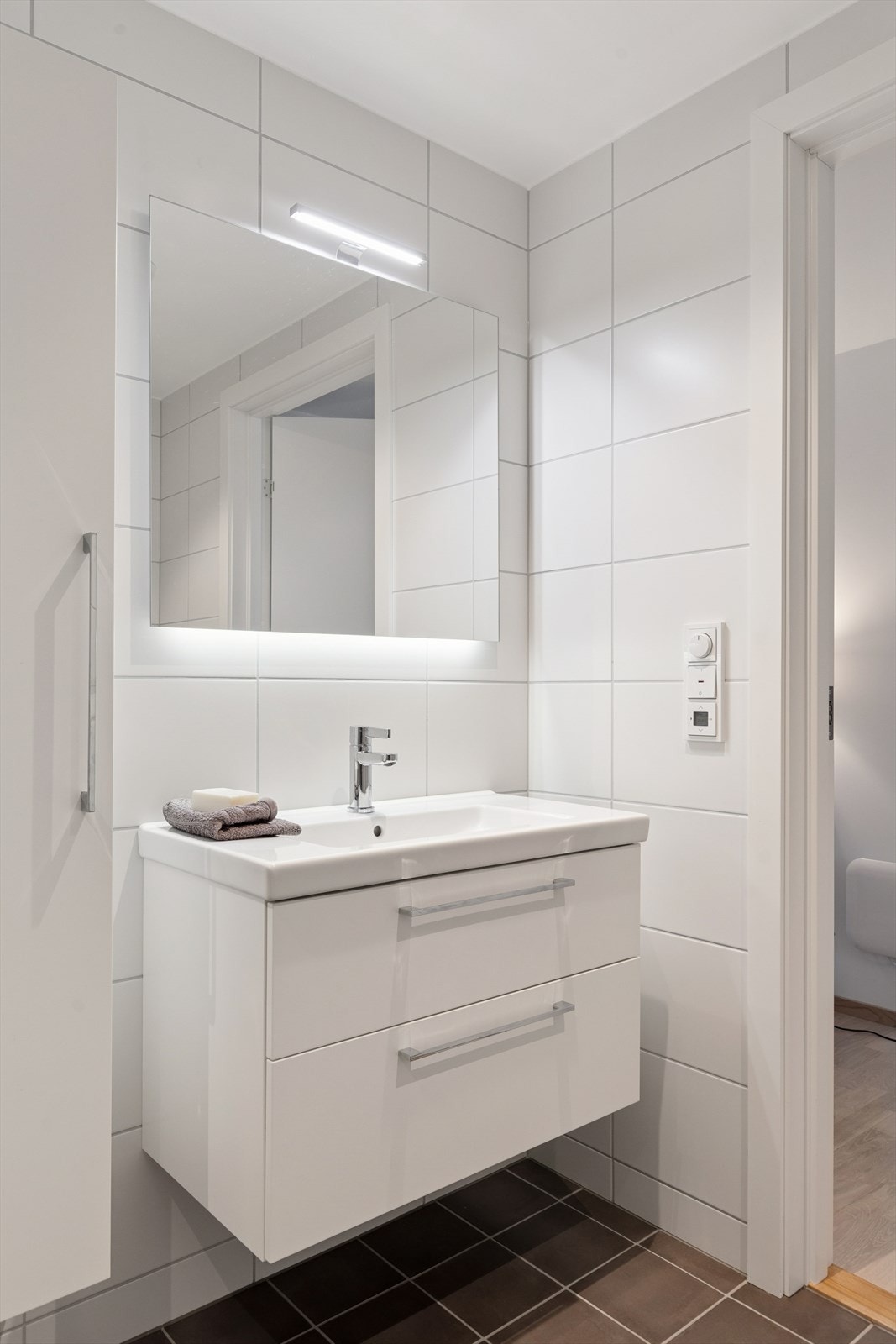 Dusjhjørne, vegghengt toalett og opplegg for vaskemaskin gjør rommet både praktisk og tidløst. Galleribilde