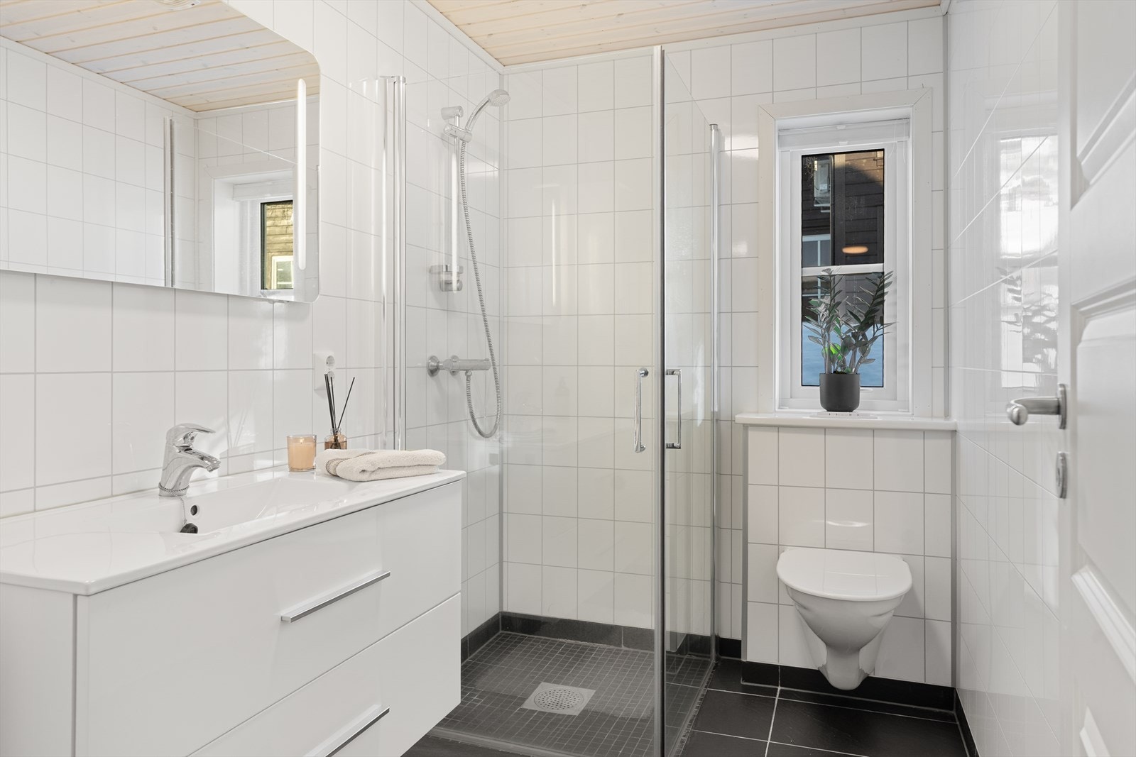 Bad i hovedetasjen er innredet med dusjhjørne, vegghengt toalett, speil og baderomsinnredning med heldekkende servant. Galleribilde