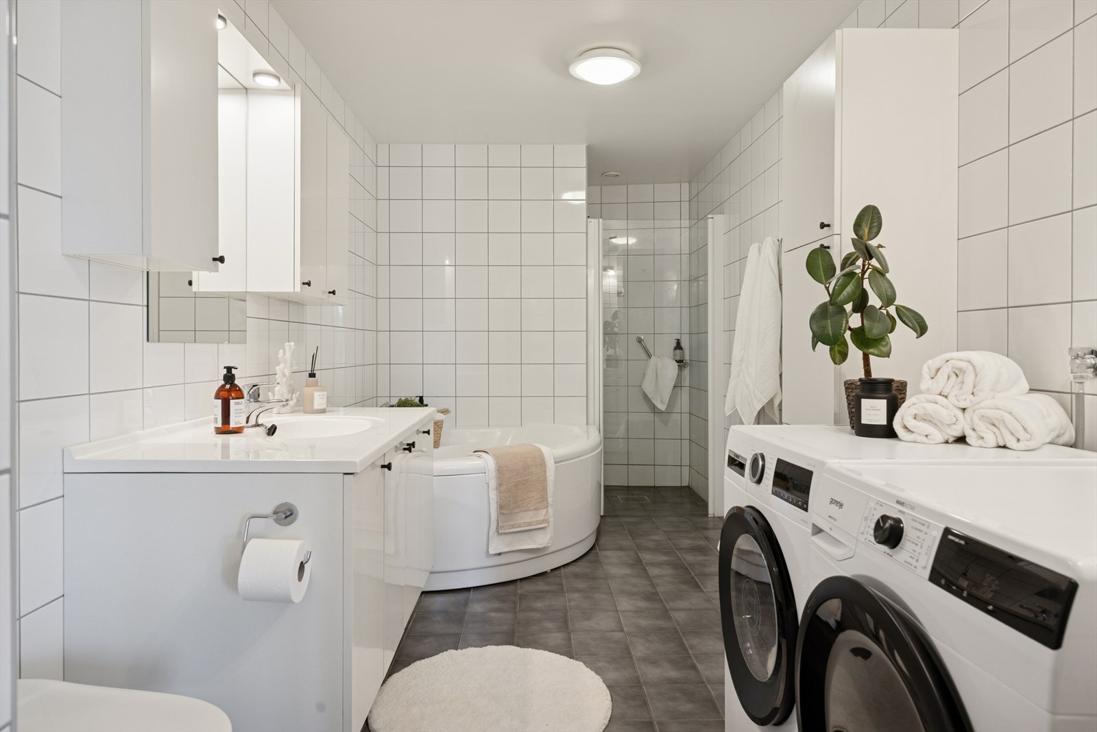 Lyst flislagt baderom med både dusj og badekar. Galleribilde