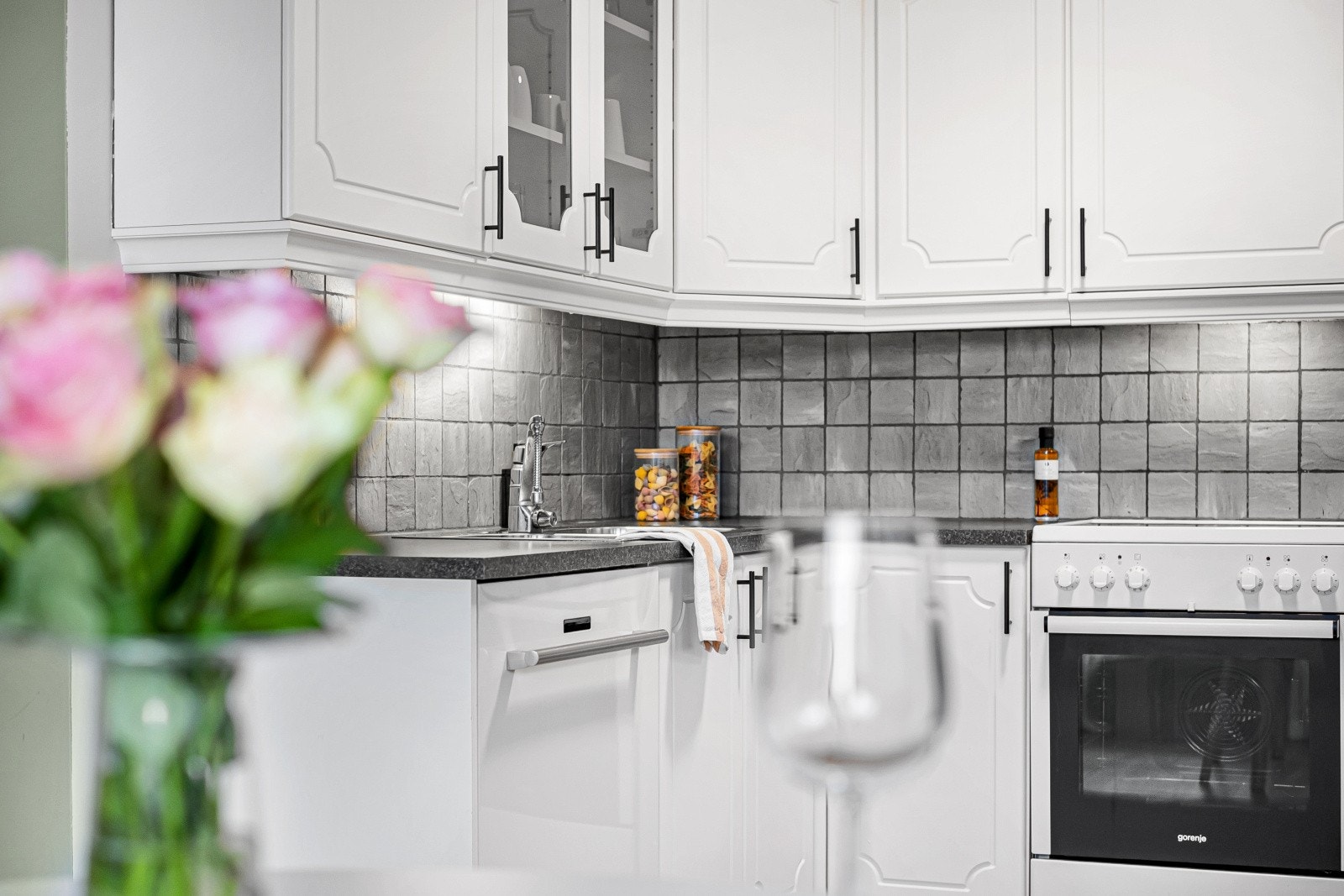 Lyst og tidløst kjøkken med profilerte fronter og benkeplate av typen laminat. Galleribilde