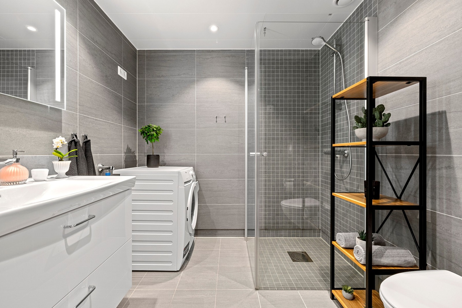 Et delikat flislagt baderom fra byggeåret 2021 med praktisk adkomst fra entréen. Galleribilde