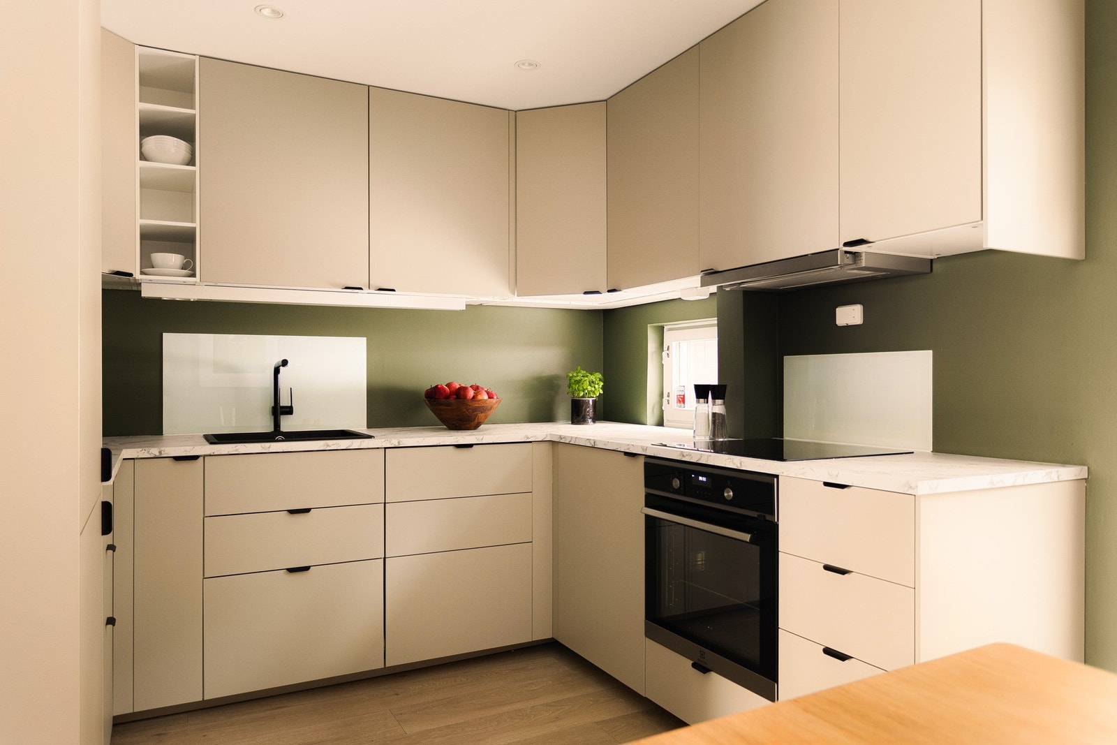 Kjøkkenet er utstyrt med nedfelt oppvaskkum i kompositt fra 2026 med ett-greps armatur, belysning og stikkontakter mellom benkeplate og overskap, samt glassplater på vegg ved oppvaskkum og platetopp. Galleribilde