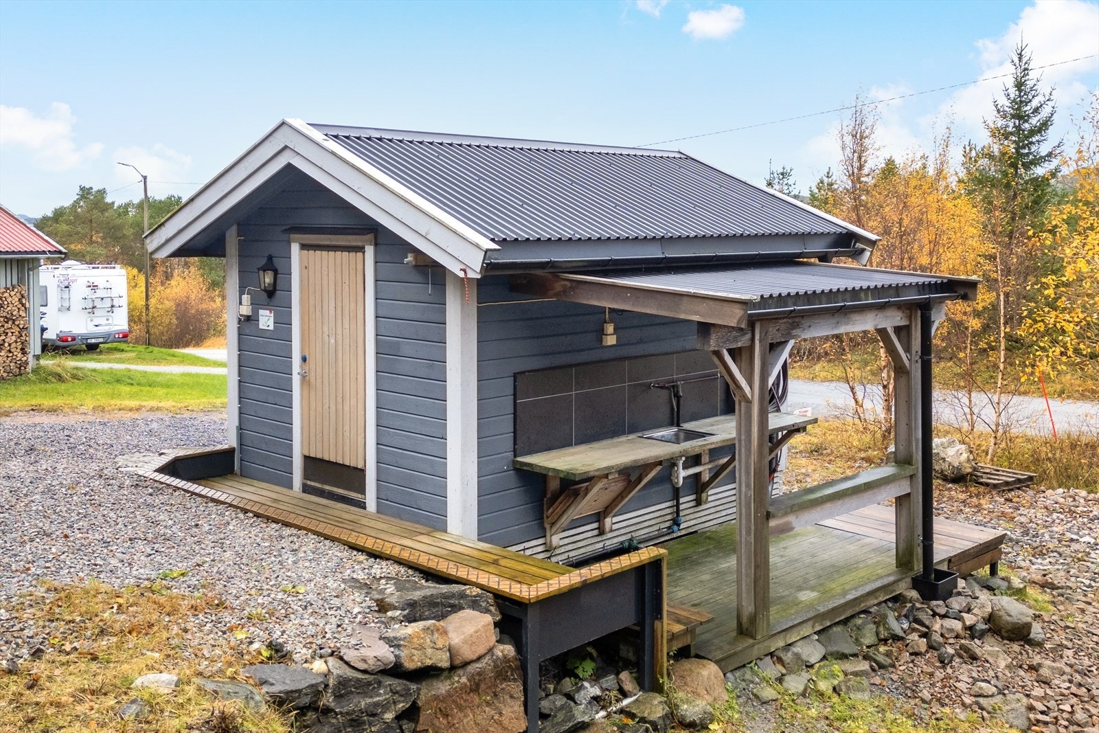 Boden er bygget med pilarer og har et utvendig overbygd sløyebenk, perfekt for praktiske gjøremål utendørs Galleribilde