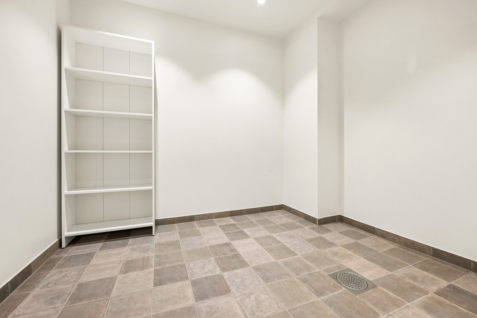 Romslig og moderne vaskerom med fliser på gulv. Rommet har opplegg for vaskemaskin. Galleribilde