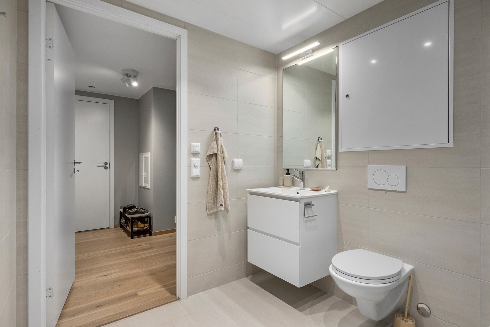 Leilighetens bad er meget delikat og moderne med store, beige fliser i gulv og på vegg og downlights i himling. Galleribilde