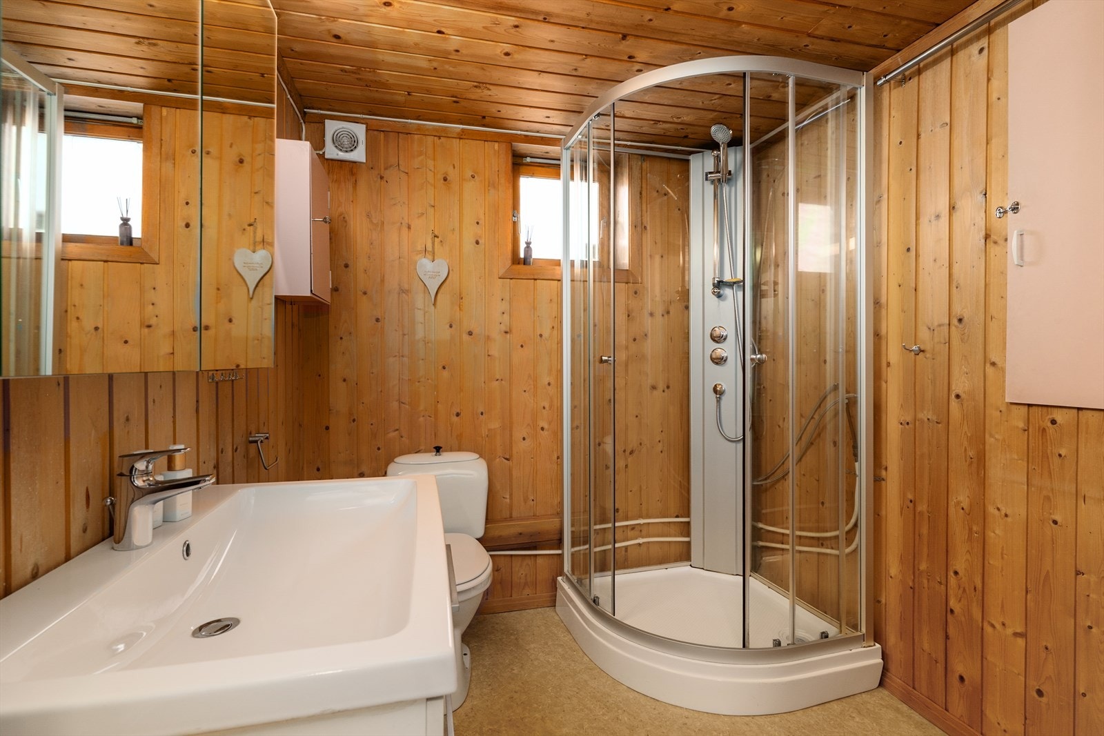 Badet i kjeller er fra 1983. Rommet inneholder heldekkende servant med underskap, speilskap og dusjkabinett som er nytt i 2021. Galleribilde