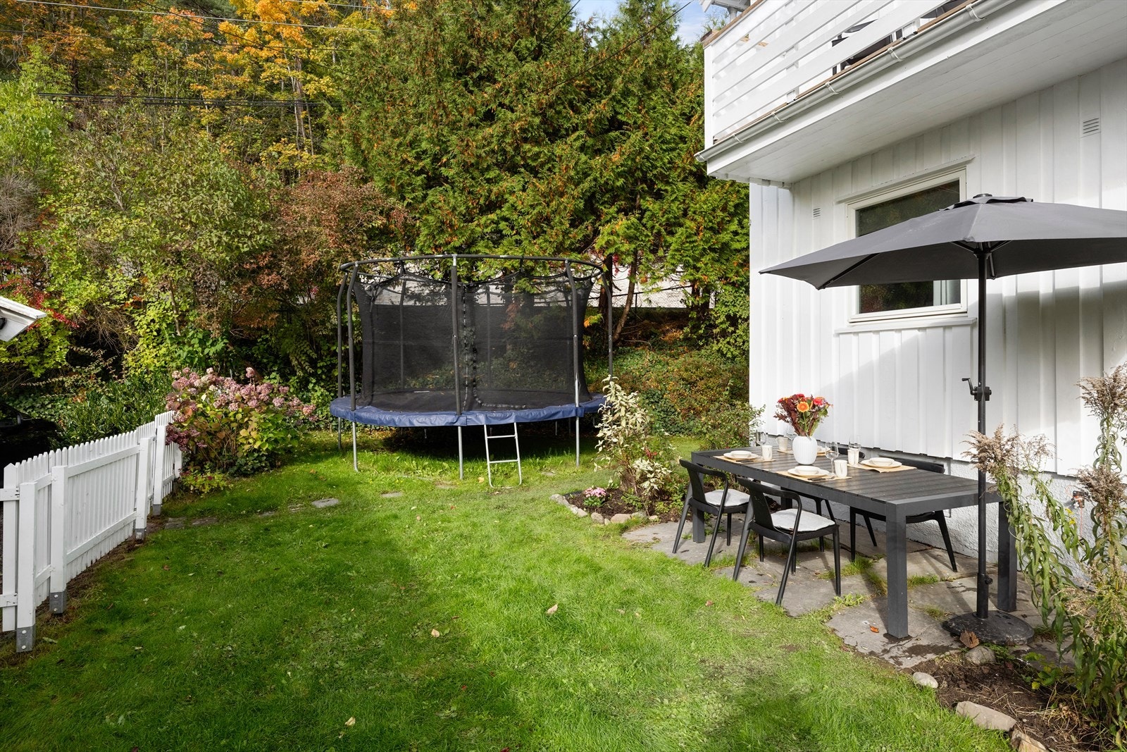 Romslig hage med plass til trampoline, lek som ballspill og flere sittesoner. Galleribilde