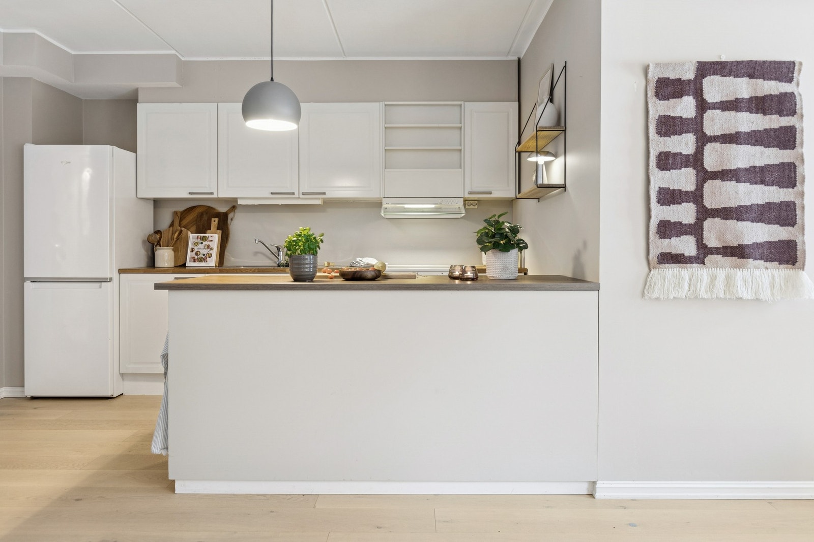 De lyse frontene, benkeplaten i trelook og overskap med integrert belysning gir rommet et varmt og ryddig uttrykk. Galleribilde