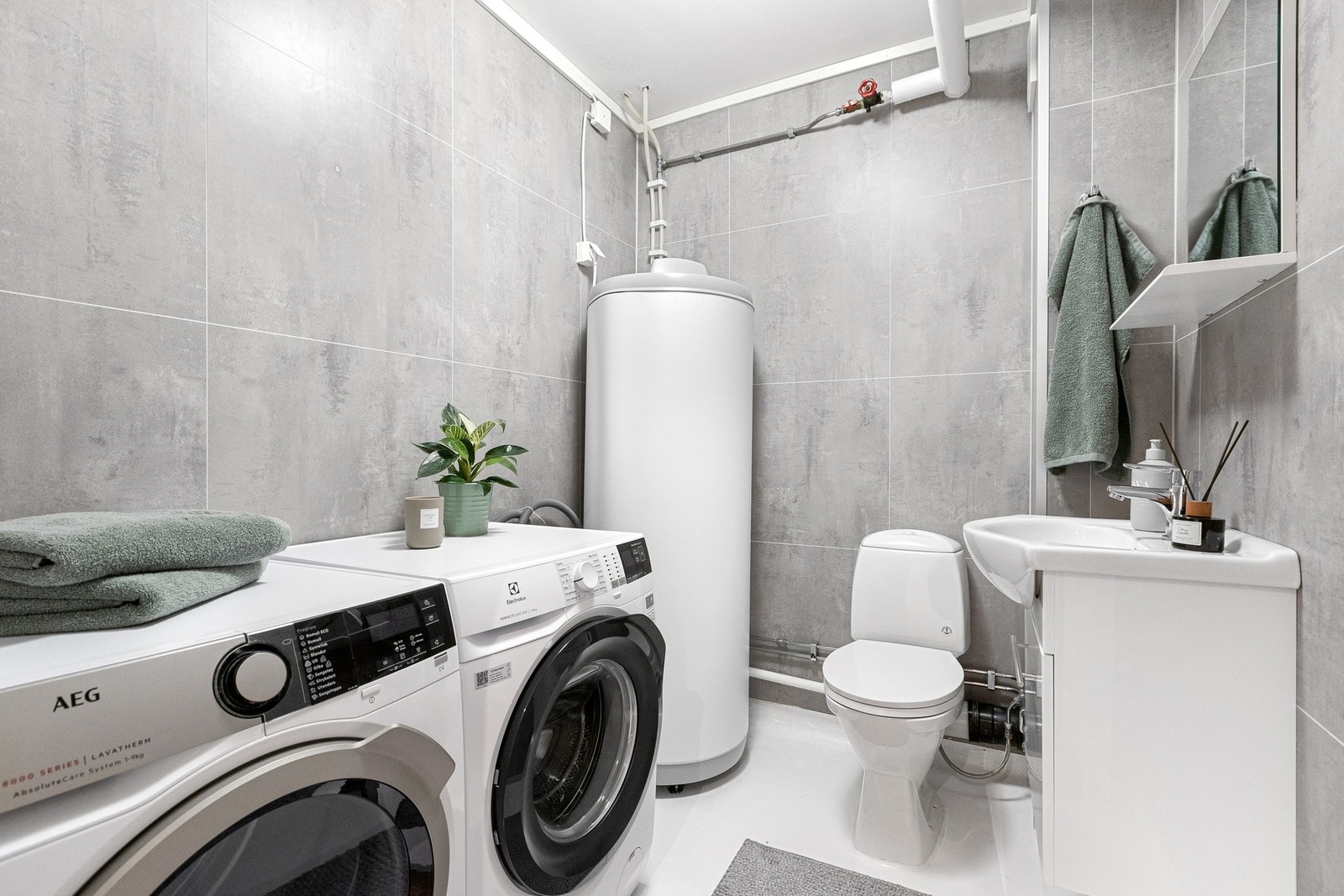 God plass til vask og tørke-maskin på vaskerommet. Gulvstående toalett. Vegghengt servant. Romslig varmtvannstank. Galleribilde