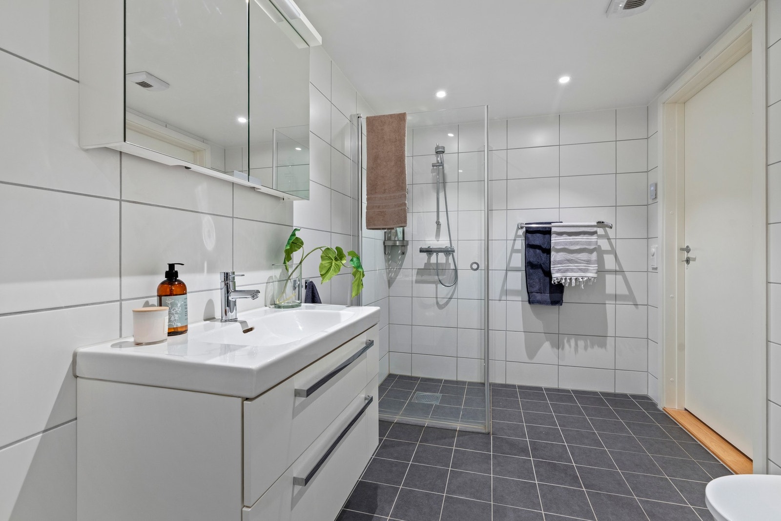 Badet er av meget god størrelse og innredningen består av en servant med slette fronter og to skuffer, samt et speilskap over servanten Galleribilde