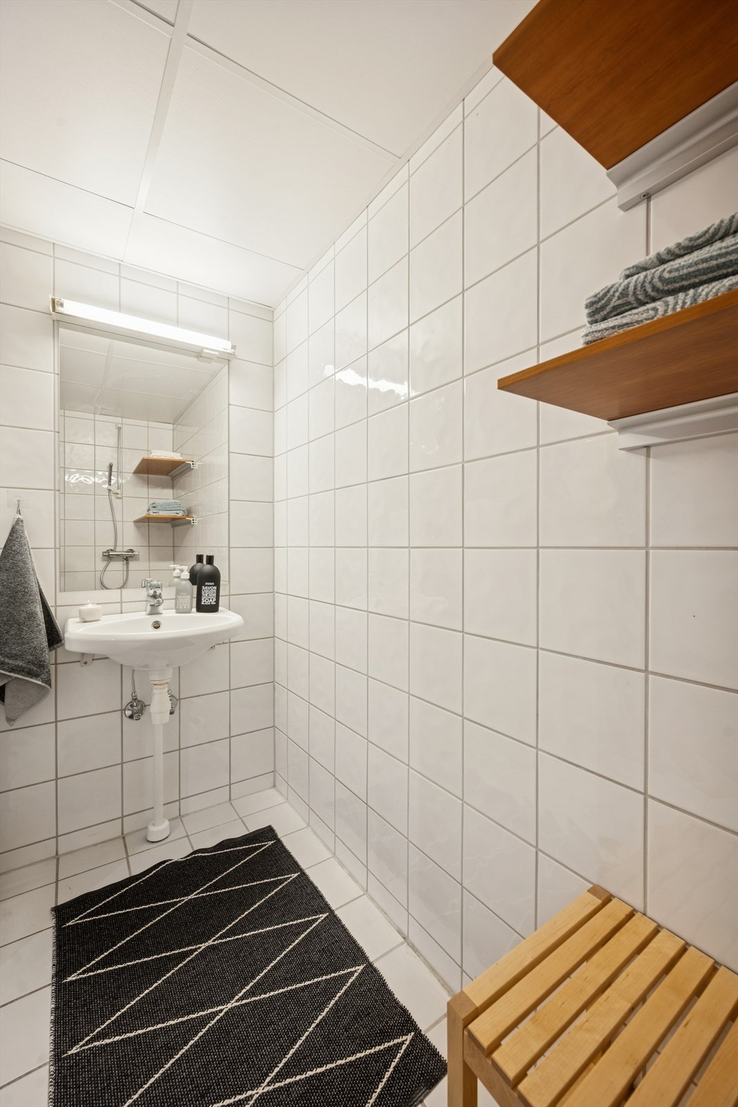 Flislagt bad med servantinnredning, dusjløsning og WC. Galleribilde