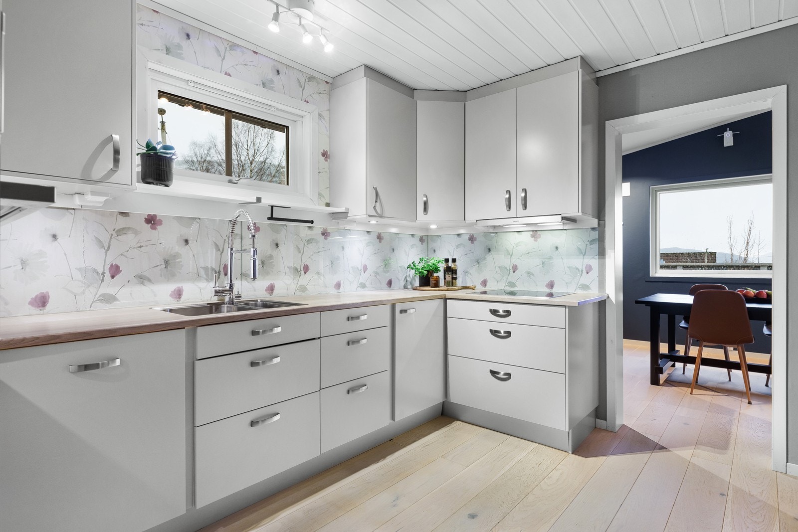 Moderne kjøkken med hvite fronter til tak og elegante stålhåndtak. Galleribilde