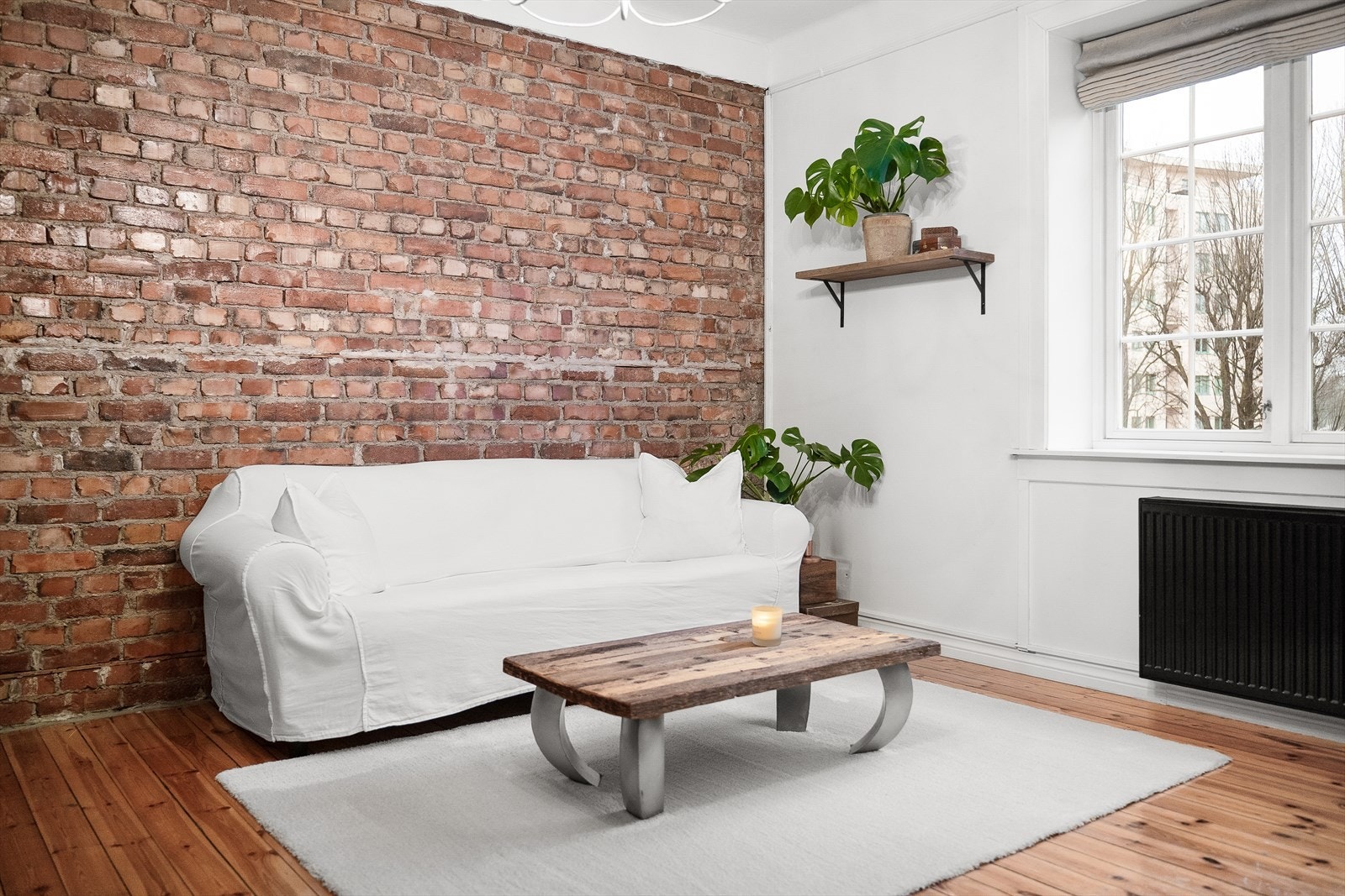 Stuen fremstår sjarmerende med vegg av behandlet teglstein og lakkert tregulv. Galleribilde